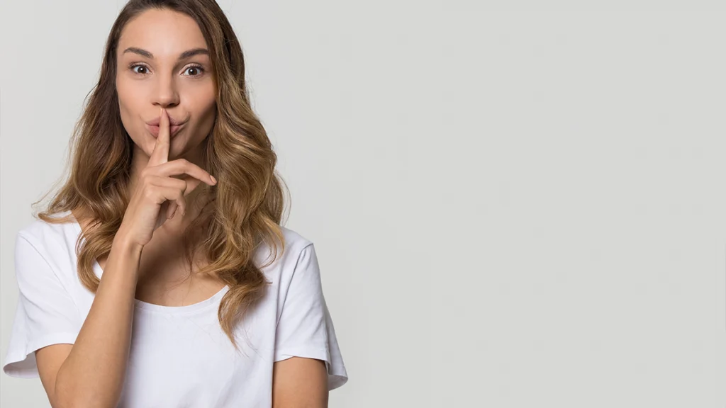 Young woman holding finger on lips to show shh